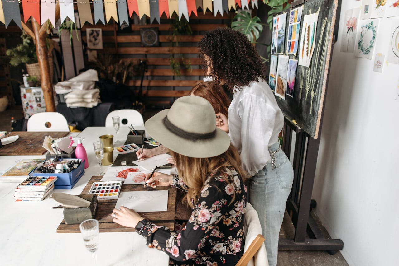 Women engaged in a creative art workshop painting with watercolors indoors.